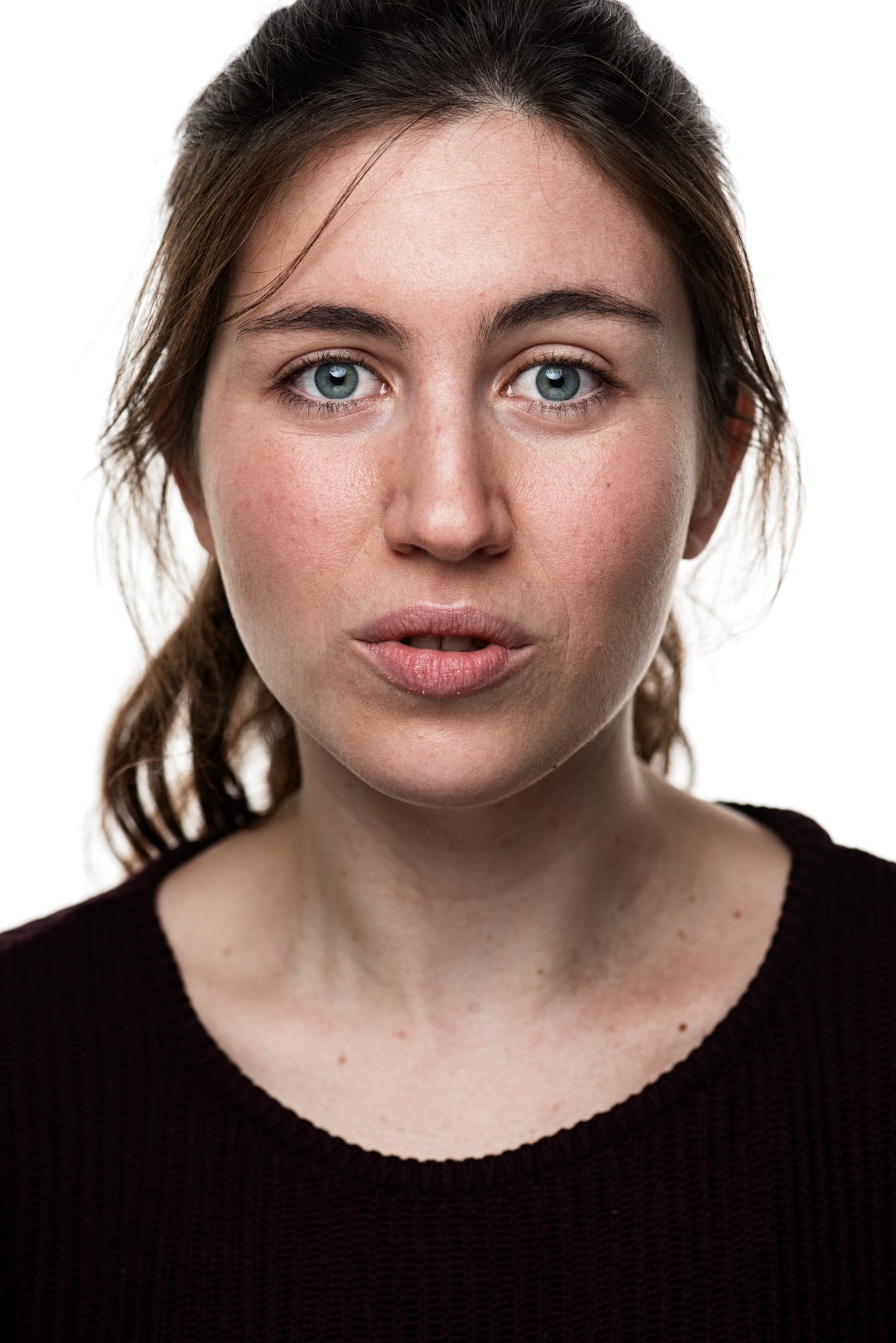 Porträt einer Frau mit braunen Haaren, die in die Kamera schaut, auf weißem Hintergrund.
