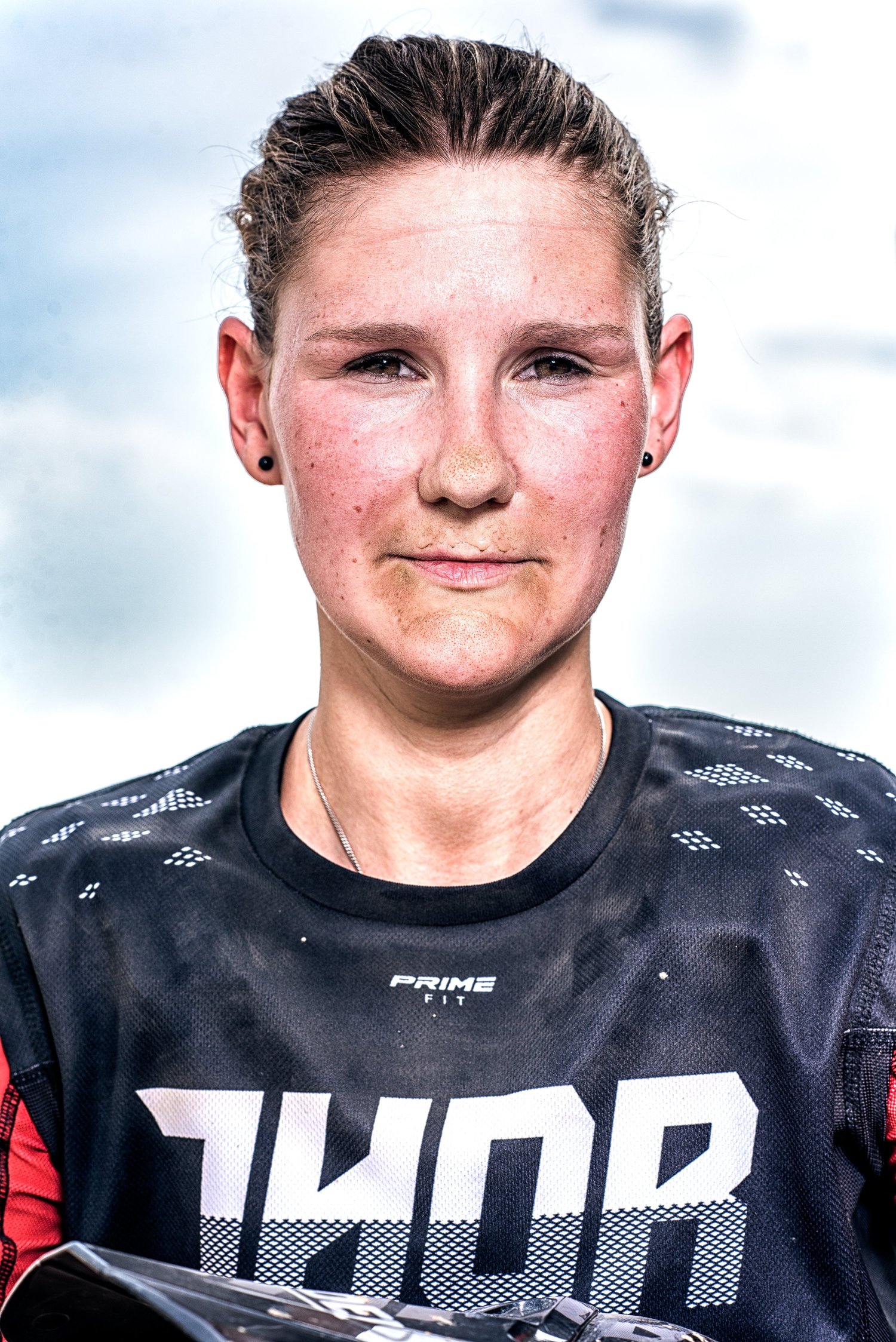 Nahaufnahme einer Person mit Sportkleidung und Schutzkleidung, staubig und mit entschlossenem Gesichtsausdruck.