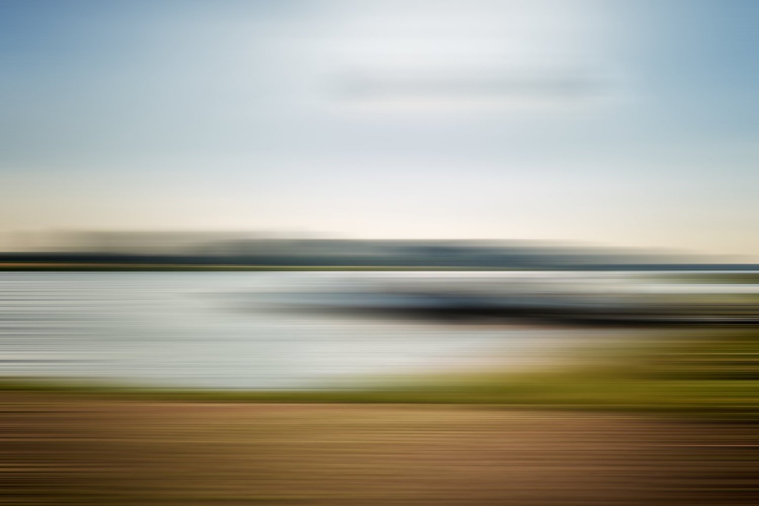 Verschwommenes Bild einer Landschaft mit Wasserfront und Himmel