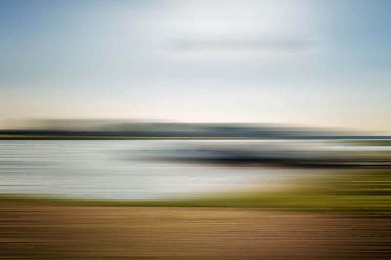 Verschwommenes Bild einer Landschaft mit Wasserfront und Himmel