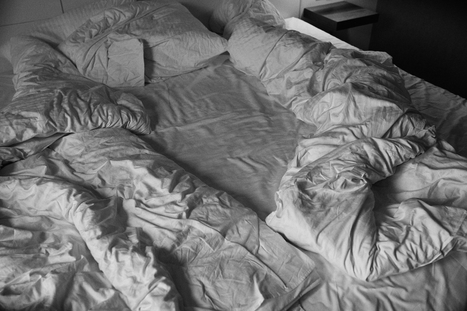Unordentliches Bett mit weißen Bettlaken und Kissen.